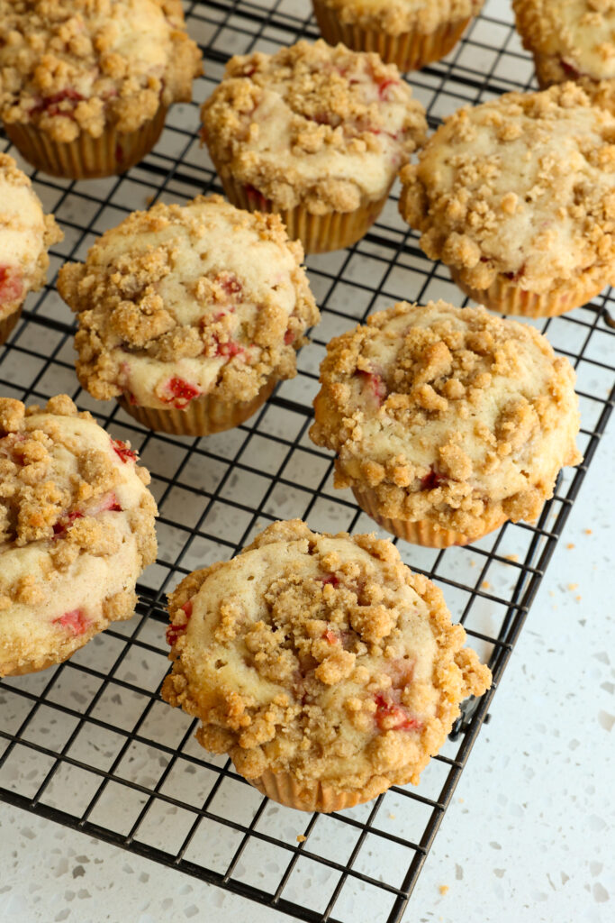 Fresh baked strawberry muffins with crumb topping on a cooling rack. 