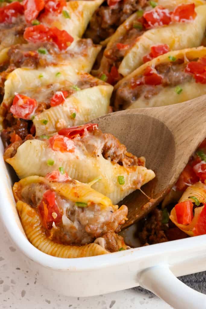 A large wooden spoon full of taco stuffed pasta shells.