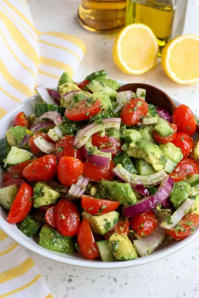 A bowl full of avocado salad with tomatoes, cucumbers, and tomatoes.