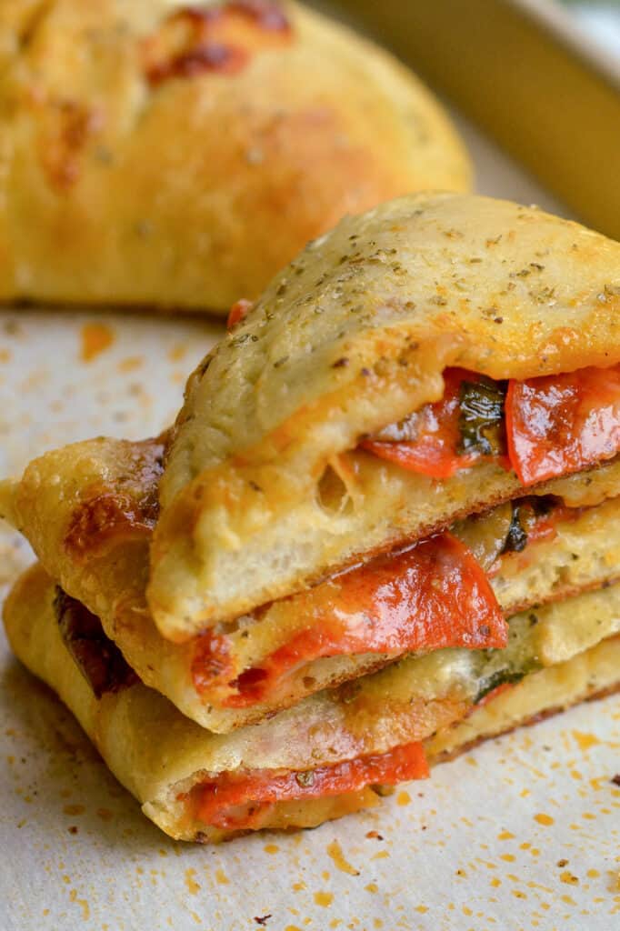 A sliced calzone filled with pepperoni , spinach, mushrooms, bell peppers, and cheese.