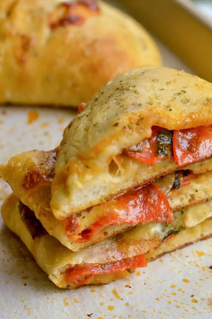 A sliced calzone filled with pepperoni , spinach, mushrooms, bell peppers, and cheese. 