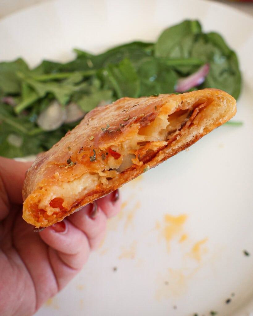 A sliced calzone filled with pepperoni , mushrooms, bell peppers, and cheese. 