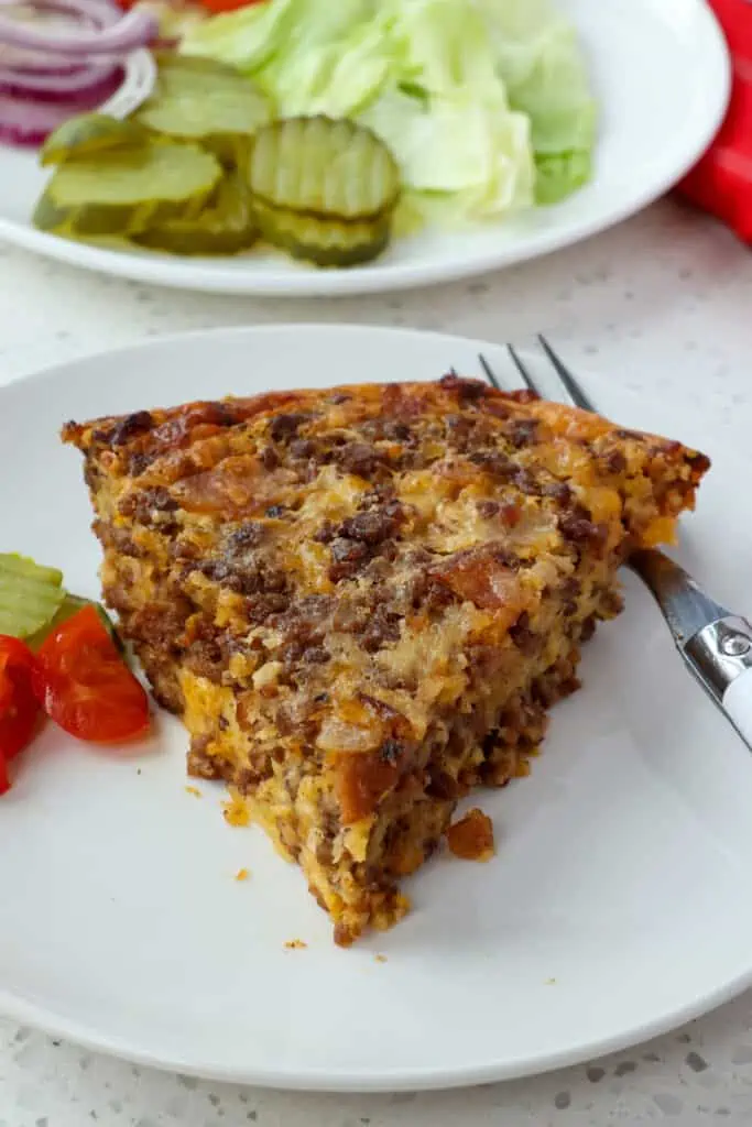 A slice of cheeseburger pie with tomatoes and lettuce.  