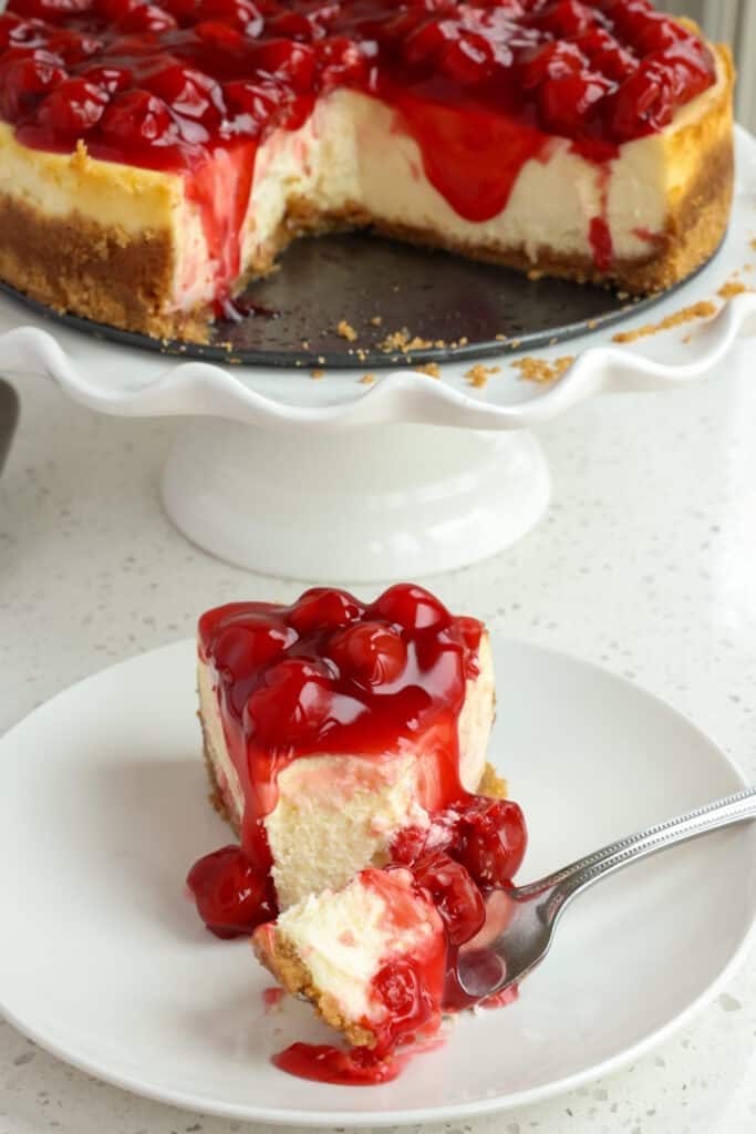 A slice of cheesecake covered with tart cherry filling.  