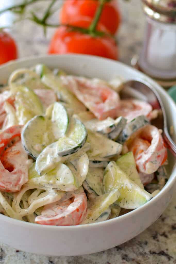 A bowl full of creamy cucumber and tomato salad