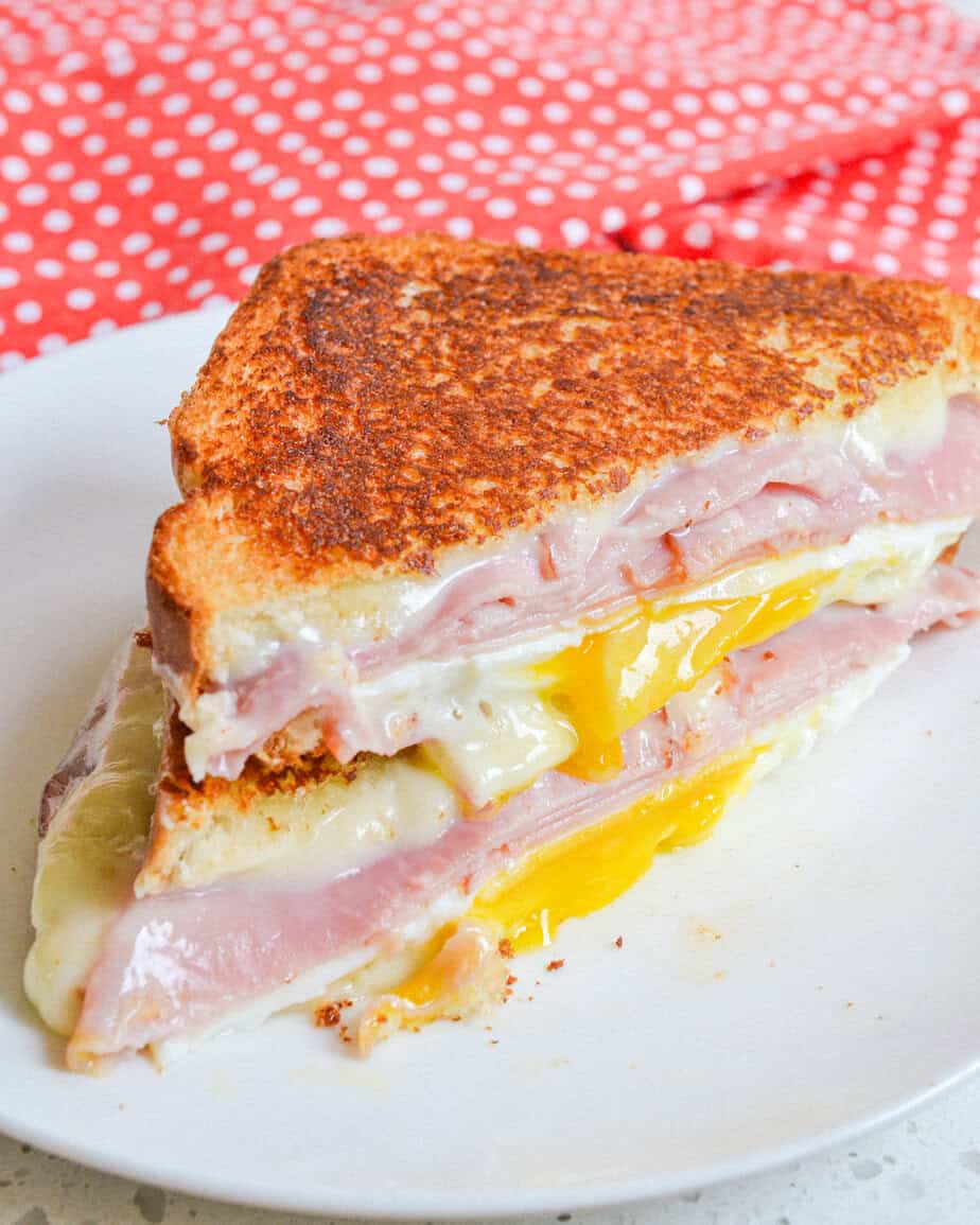 A close up view of a fried egg sandwich with ham and cheese. 