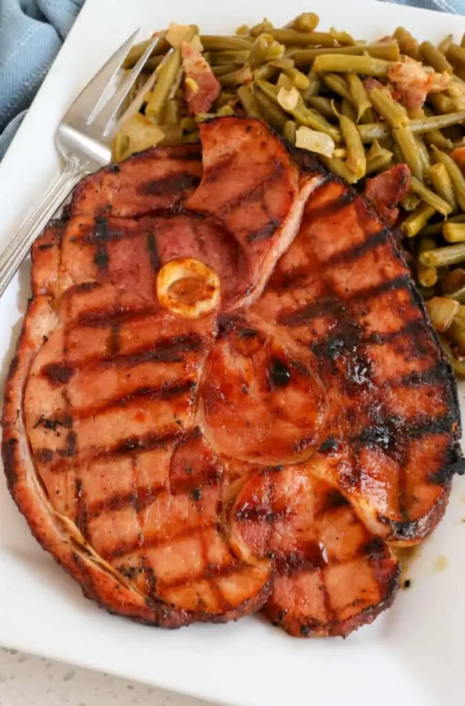Brown sugar glazed ham steak with southern green beans on a platter