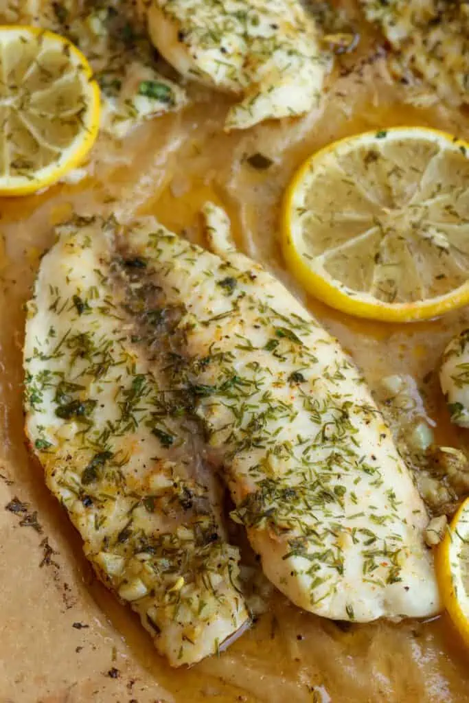 Baked lemon dill tilapia filets on a baking sheet covered with parchment paper.  