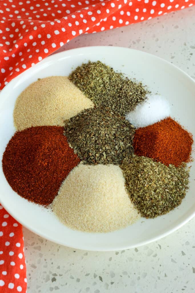 A plate full of the various spices and herbs that make Creole Seasoning. 