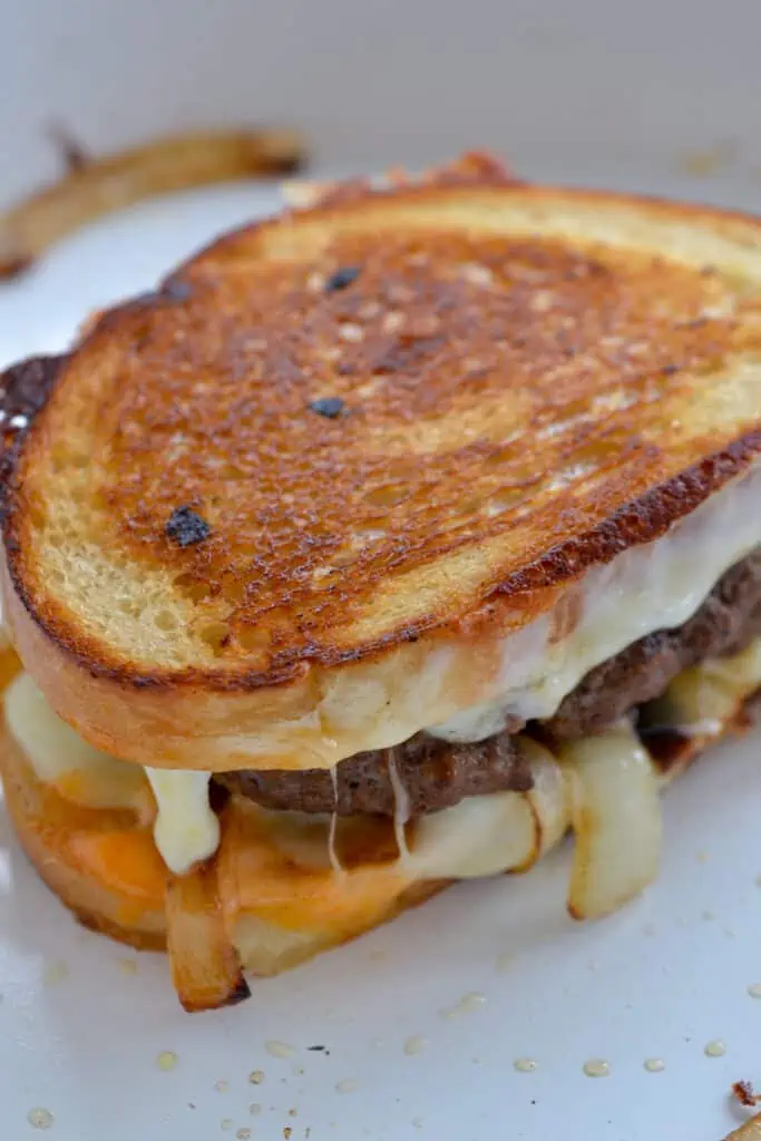 Patty melt with caramelized onions in a skillet. 