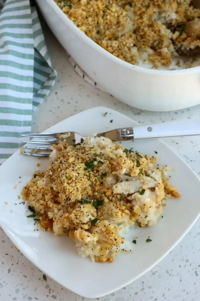 A plate full of chicken casserole with rice, homemade cream of chicken soup. poppy seeds, and a buttery crumb topping. 