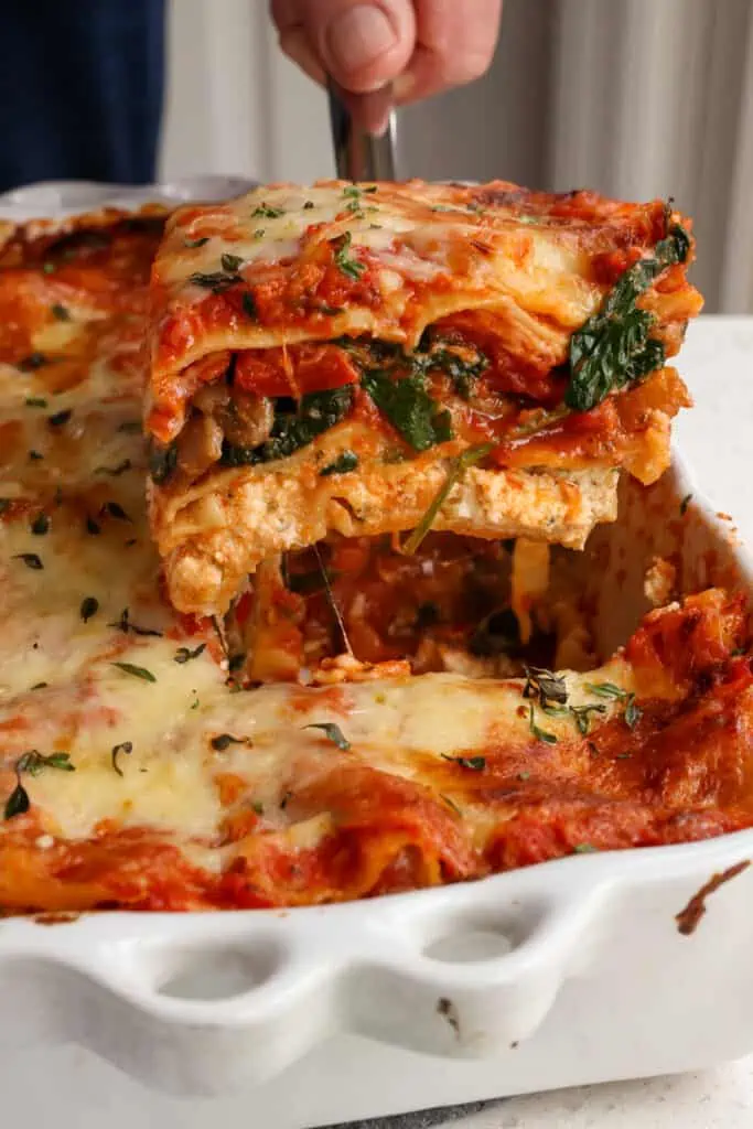 A slice of vegetable lasagna on a spatula.  