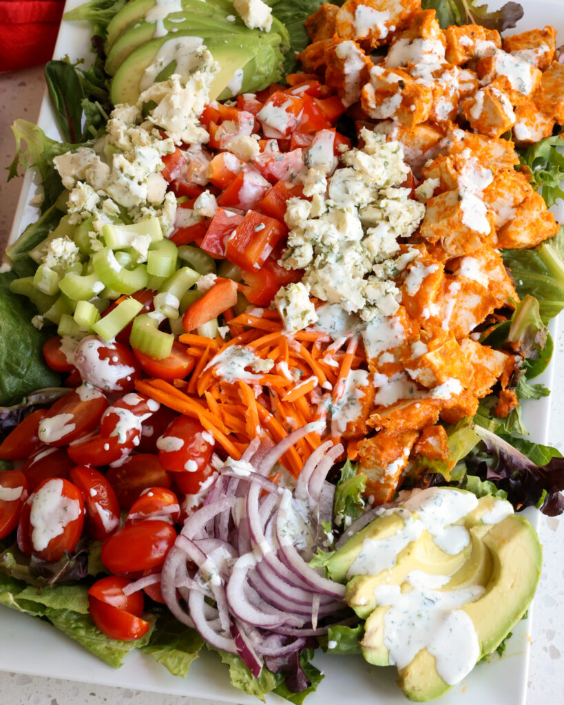 Buffalo Chicken Salad with tomatoes, celery, red bell peppers, carrots, avocados, buffalo chicken and bleu cheese.  