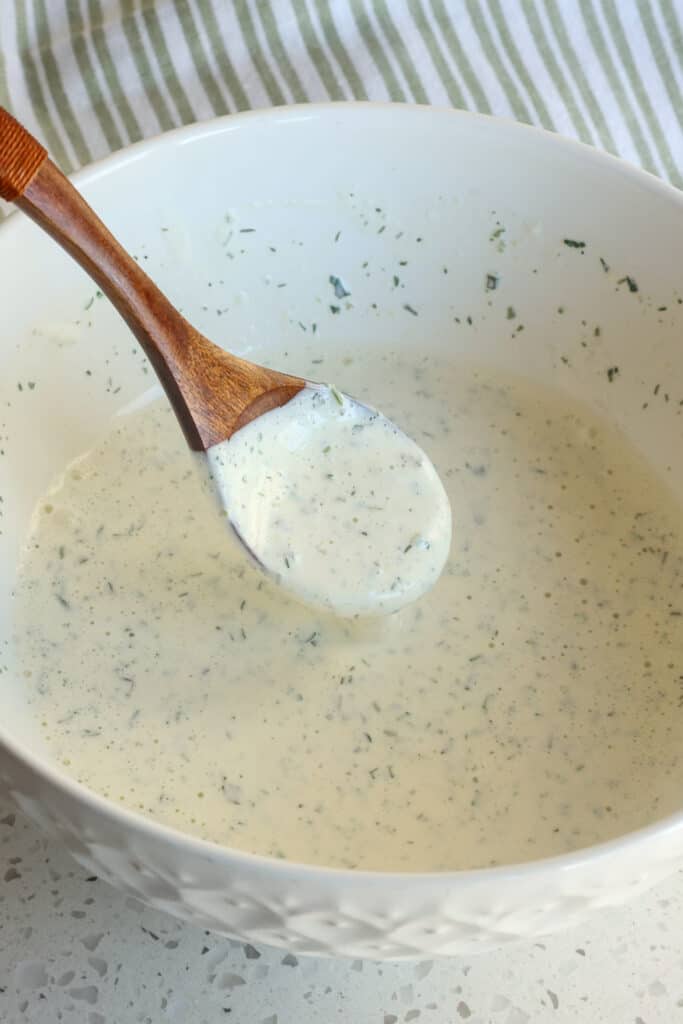 A spoonful of homemade ranch dressing in a mixing bowl. 
