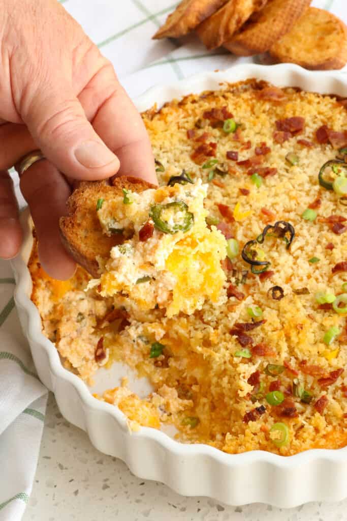 A crostini with warm jalapeno popper dip on it.