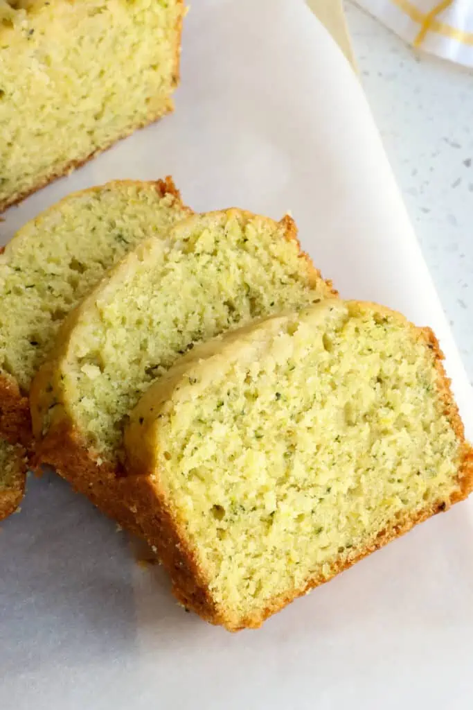 Three slices of lemon zucchini bread on a cutting board. 