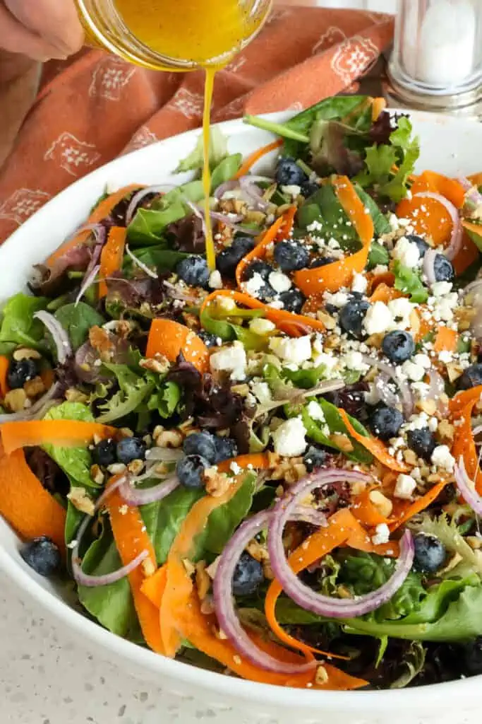 A large bowl of spring mix salad with orange vinaigrette. 