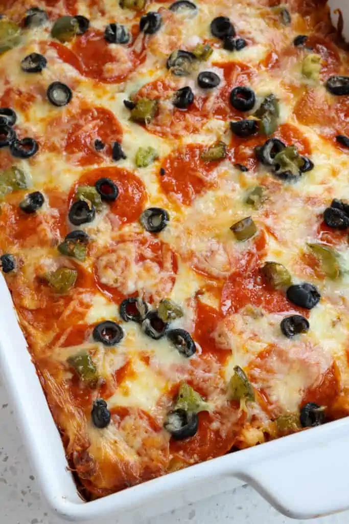 An easy Pizza Casserole with pasta, Italian Sausage, onions, garlic, green bell peppers, pepperoni, and black olives in marinara sauce topped with oodles of melted mozzarella cheese. 