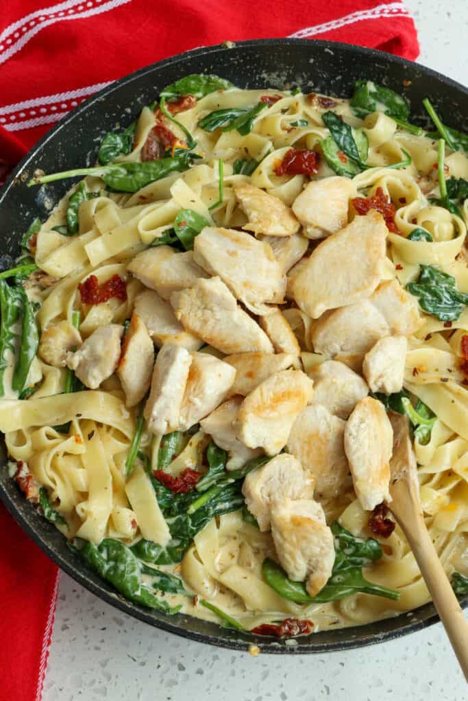 Tuscan Pasta with browned chicken pieces in a skillet. 