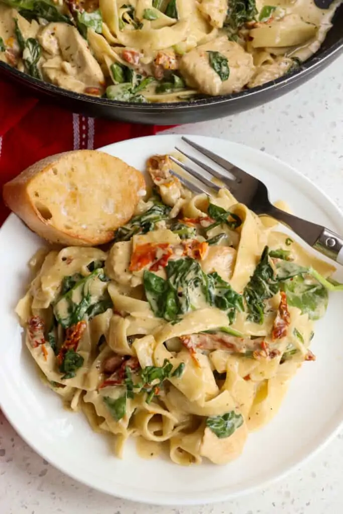 This Creamy Tuscan Chicken Pasta Recipe combines browned chicken breast pieces, fresh baby spinach, sundried tomatoes, garlic, and fettucine pasta in an Italian seasoned rich creamy garlic Parmesan Cheese sauce.