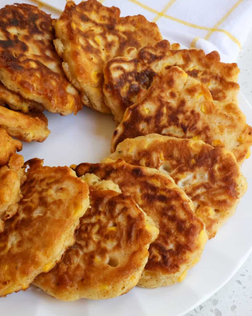A white circular plate full of corn fritters.