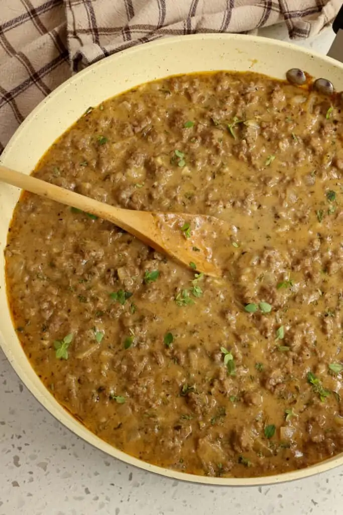A skillet full of creamy hamburger gravy with thyme, parsley, and nutmeg. 