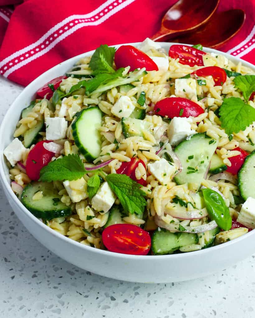 An overhead view of orzo pasta salad with cucumbers, tomatoes, and feta. 