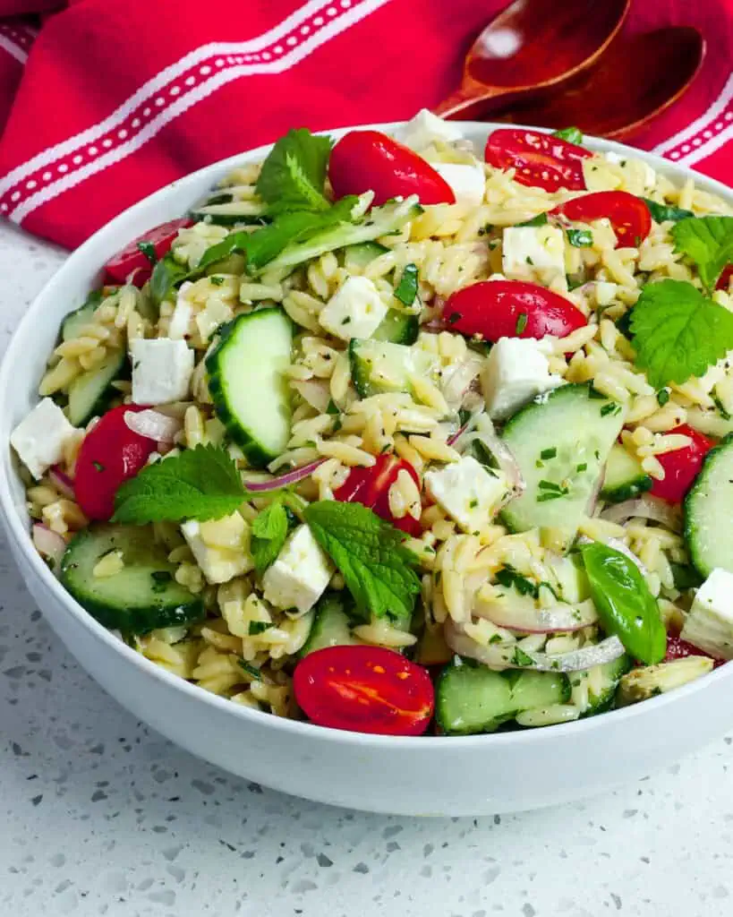 An overhead view of orzo pasta salad with cucumbers, tomatoes, and feta. 