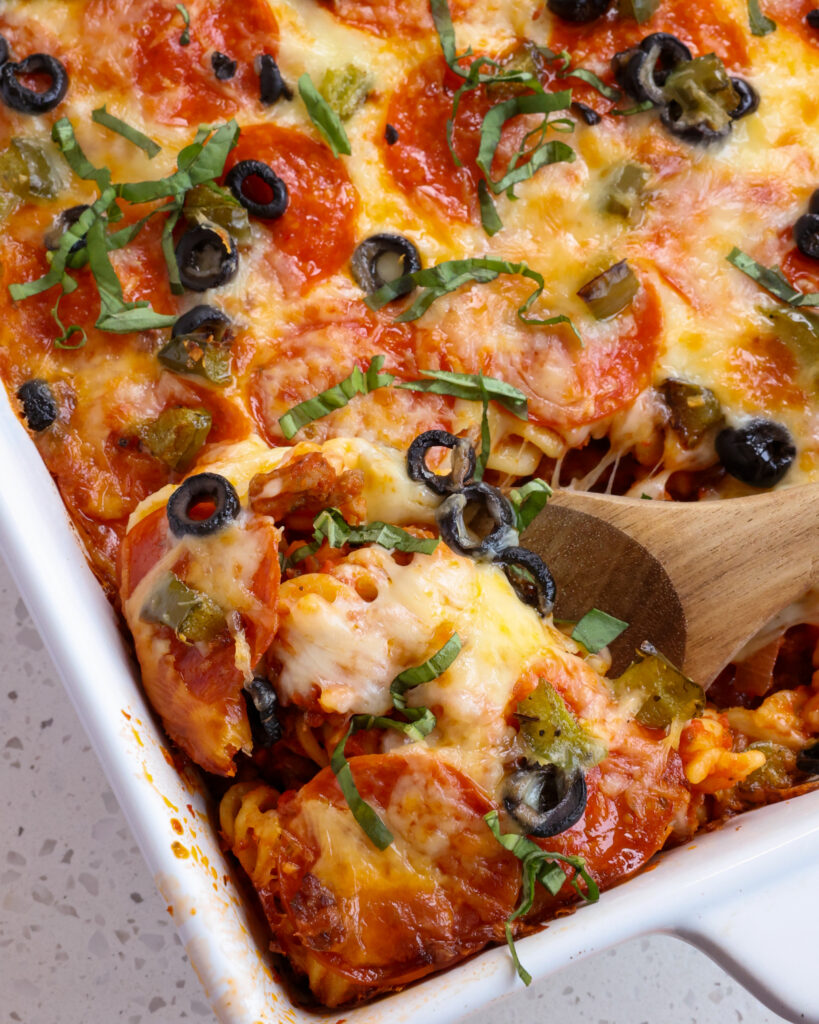 This Baked Pizza Casserole Recipe combines rotini pasta, Italian sausage, onions, garlic, bell peppers, pepperoni, and black olives all in smothered with pizza marinara sauce blend and baked with a blanket of mozzarella cheese. 