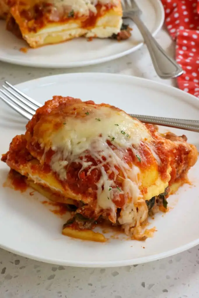 A slice of lasagna ravioli on a plate with a fork. 