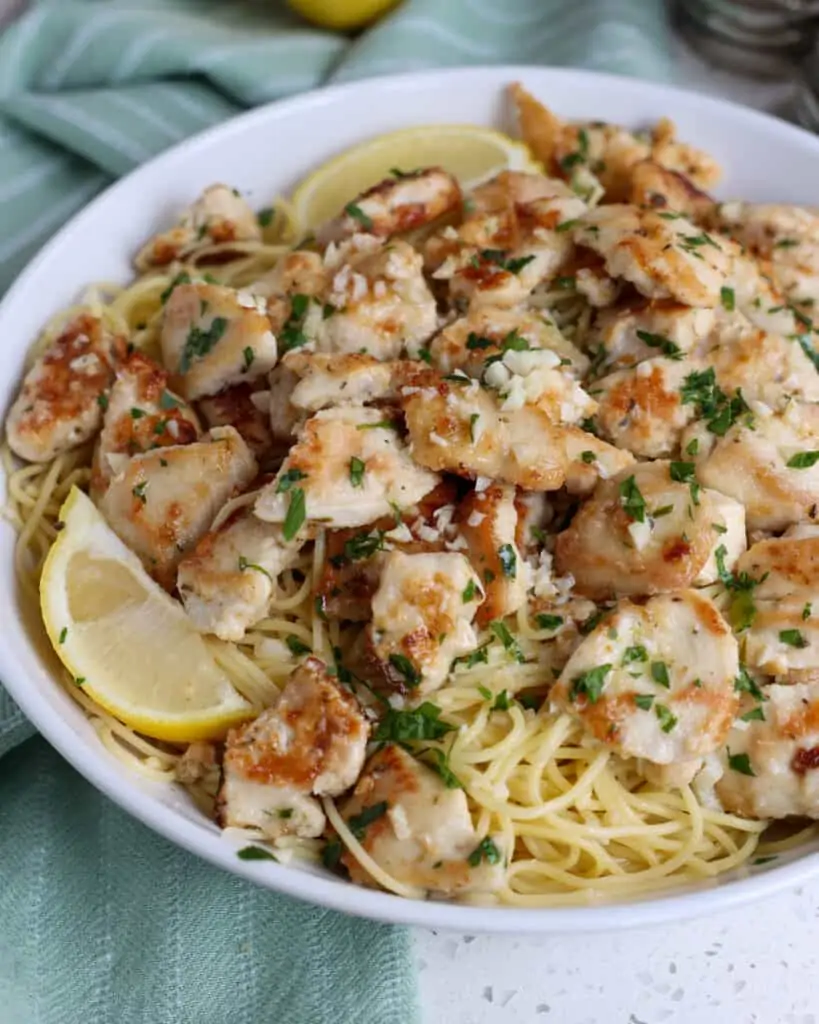 A scrumptious and easy Chicken Scampi recipe made with lightly breaded chicken bites, garlic, white wine, lemon juice, and parsley all on a bed of pasta topped with freshly grated Parmesan Cheese.