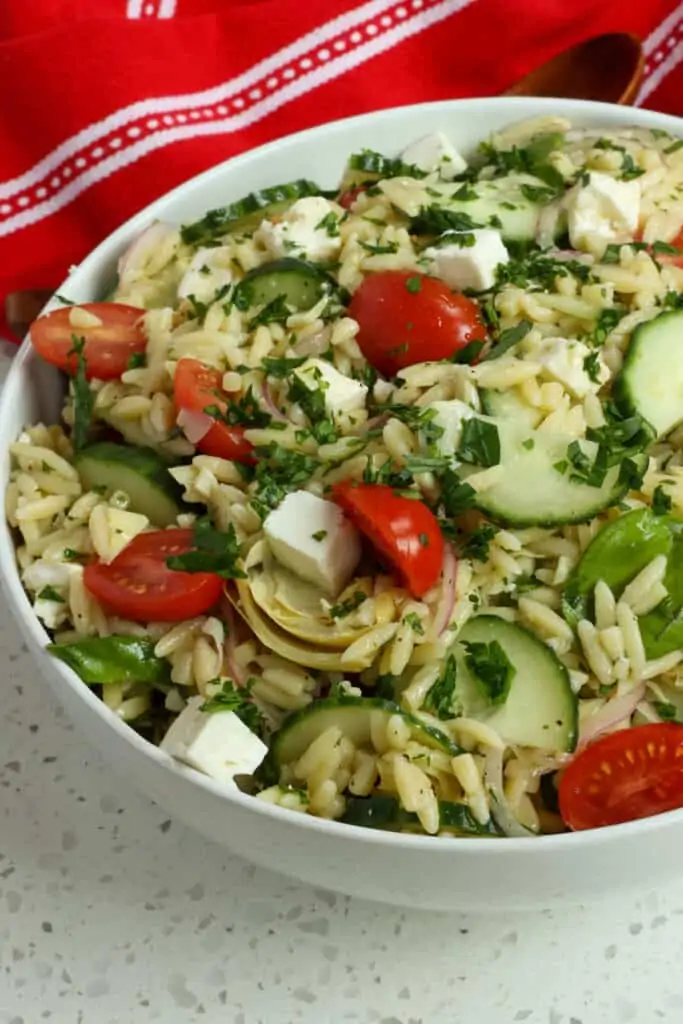 A delicious quick and easy Orzo Pasta Salad with English cucumbers, sun ripened tomatoes, artichoke hearts, red onion, and feta cheese all tossed in a lemon mustard vinaigrette with fresh herbs