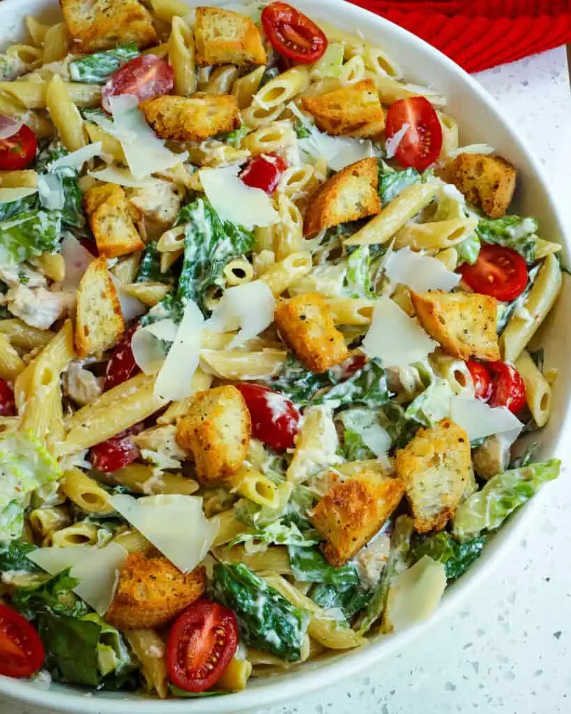 A close up view of Chicken Caesar Pasta Salad in a large white serving bowl. 