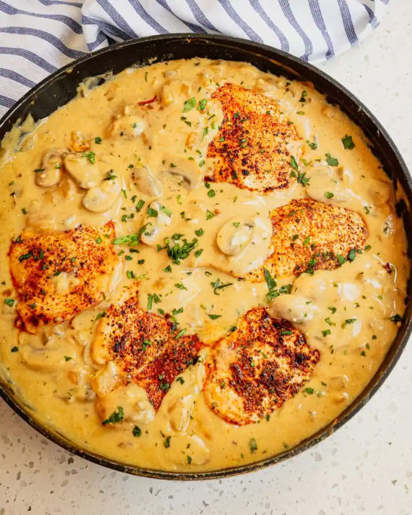 An overhead view of chicken stroganoffin a black skillet. 