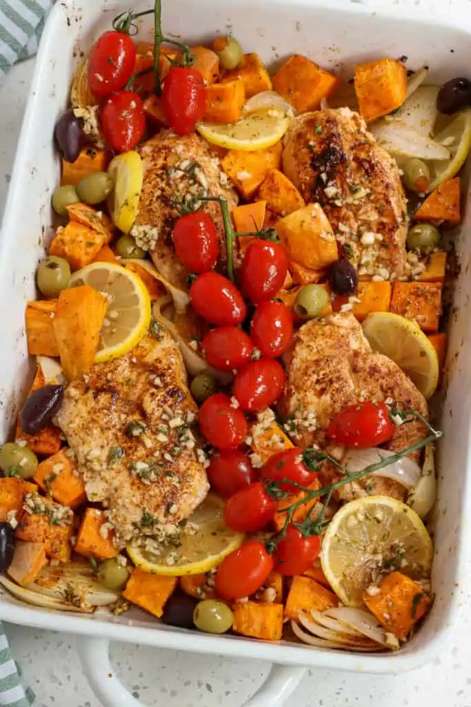 Greek Chicken with sweet potatoes, onions, tomatoes, olives, lemon slices, and feta cheese all drizzled with a lemon and rosemary marinade. 