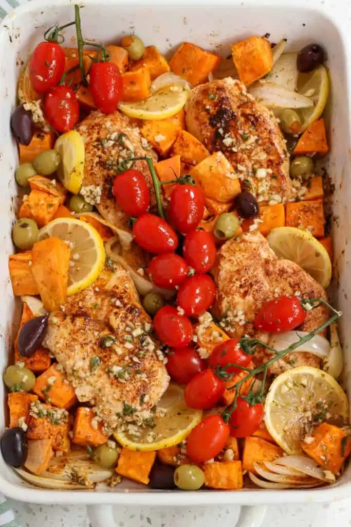 Tasty Greek Chicken combines chicken breasts, sweet potatoes, onions, tomatoes, Kalamata olives, green olives, lemon slices, and feta cheese all drizzled with a lemon, rosemary, and thyme marinade. 