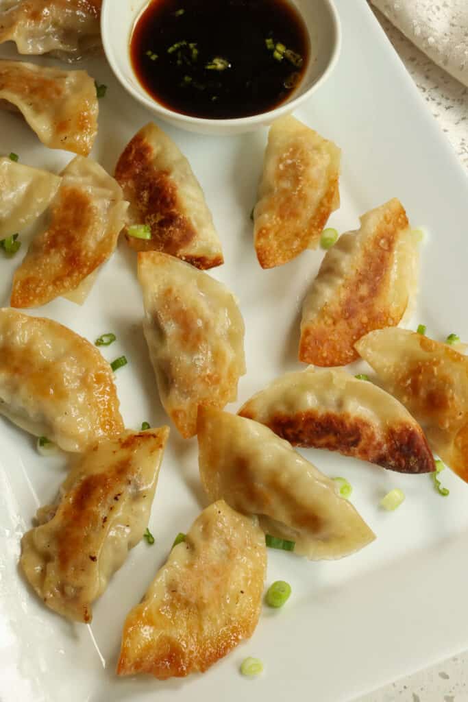 This Gyoza Recipe is cabbage and ground pork stuffed dumplings pan fried and steamed to perfection  served with sweet and salty three ingredient sauce. 