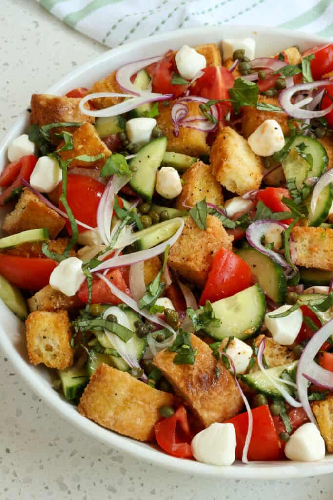 This tasty Italian Panzanella Salad combines toasted bread with fresh sun-ripened tomatoes, mozzarella pearls, thin slices of red onion, English cucumbers, capers, and fresh basil all drizzled with an easy vinaigrette.