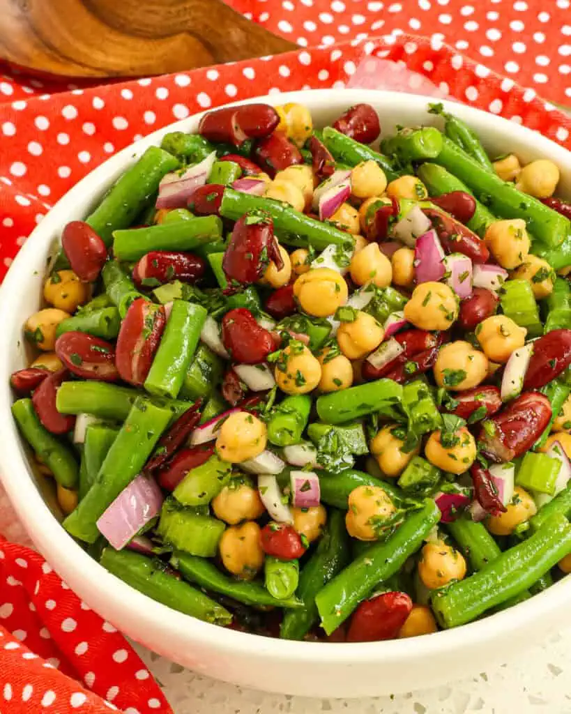 This classic Three Bean Salad brings green beans, garbanzo beans, and kidney beans together in a sweetened oil and vinegar dressing seasoned with fresh parsley and rosemary.