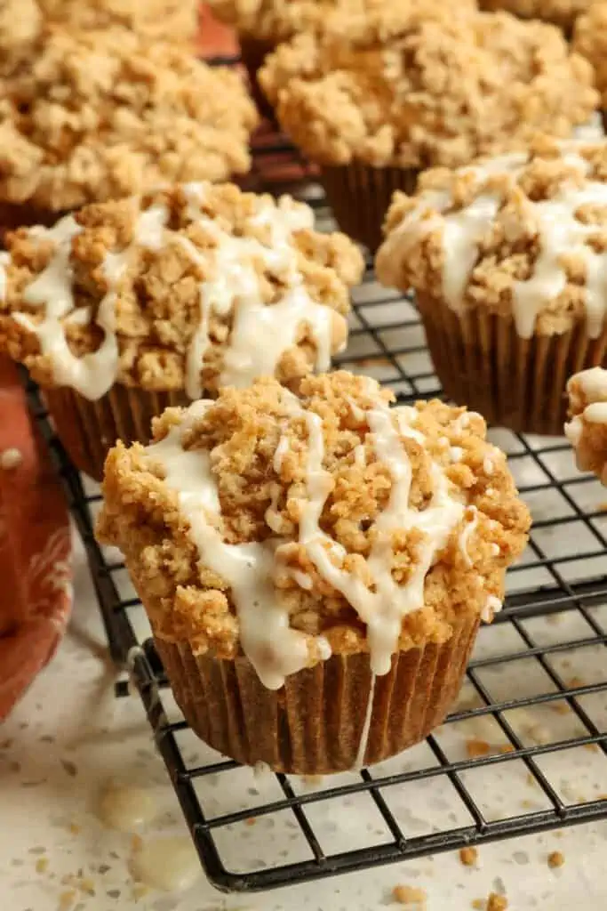 Moist Pumpkin Muffins with a perfect blend of pumpkin pie spice, a mile-high crumb topping, and a cinnamon maple drizzle.   Bring fall in with a smile and bake a batch of these tasty muffins 