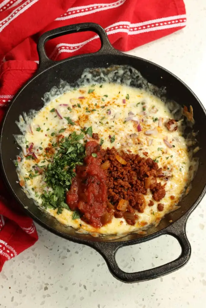 Queso Fundido is a dip with creamy melted cheese, chorizo, spices and toppings served with tortilla chips or tortillas. 