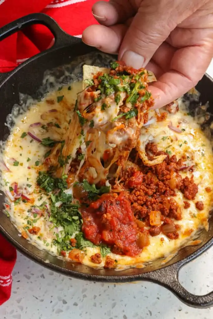 Queso Fundido is layered with melted cheese, chorizo, sauteed onions and topped with diced tomatoes, and minced jalapenos. 