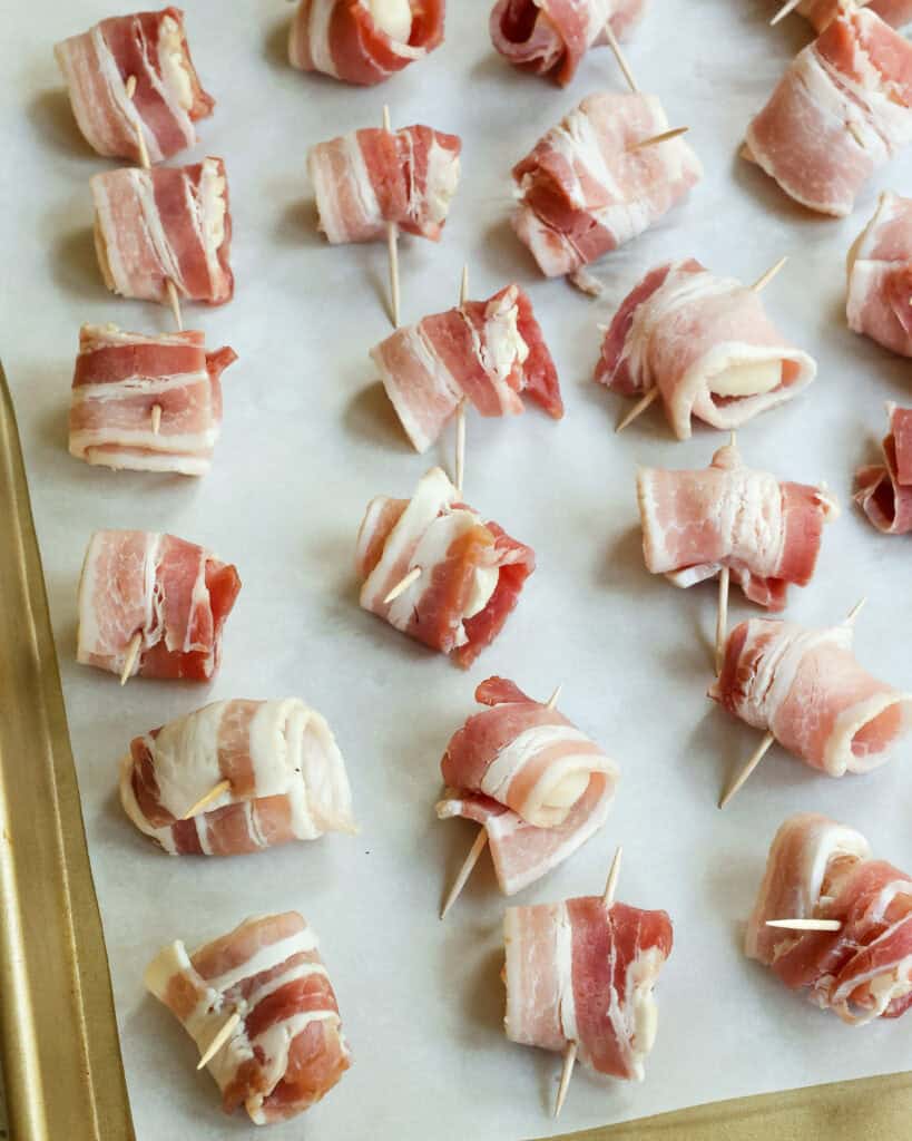 Cut the bacon strips in half, then wrap each piece around a water chestnut and secure with a toothpick. Place on a baking sheet.