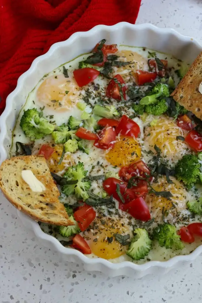 These Easy Baked Eggs are made easy in a shallow casserole dish or in individual ramekins and customized with steamed broccoli, chopped tomatoes, fresh herbs. and grated Parmesan cheese or grated Asiago cheese. 