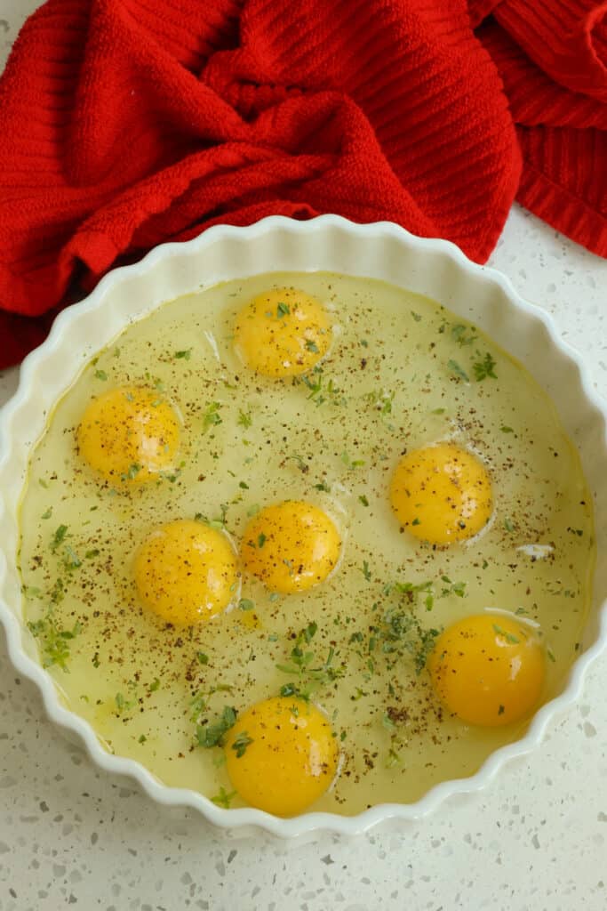 Crack the eggs in the dish and sprinkle with about 1 tablespoon of fresh herbs like thyme, rosemary, and Italian parsley.