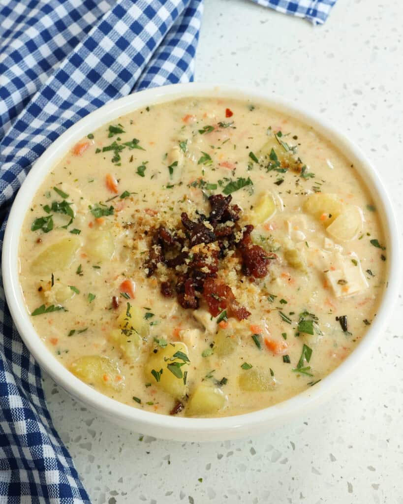 Chicken Potato Soup in a white bowl with a blue towel to the left.