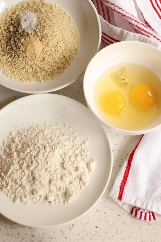 First setup the breading stations.  Add the flour to a rimmed plate or shallow bowl.  Then whisk together the eggs and Dijon Mustard together in a shallow bowl.  Combine the Panko Breadcrumbs, salt, black pepper, and garlic powder on another rimmed plate or in a shallow bowl. 