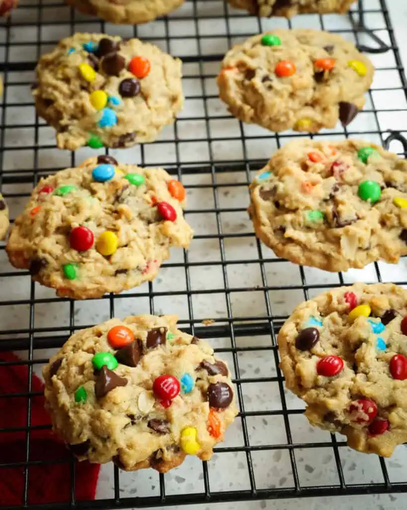 A batch of monster cookies on a cooling rack. 