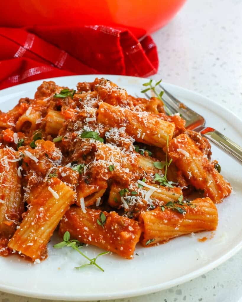 Pasta Bolognese served on a plate garnished with Parmesan cheese.