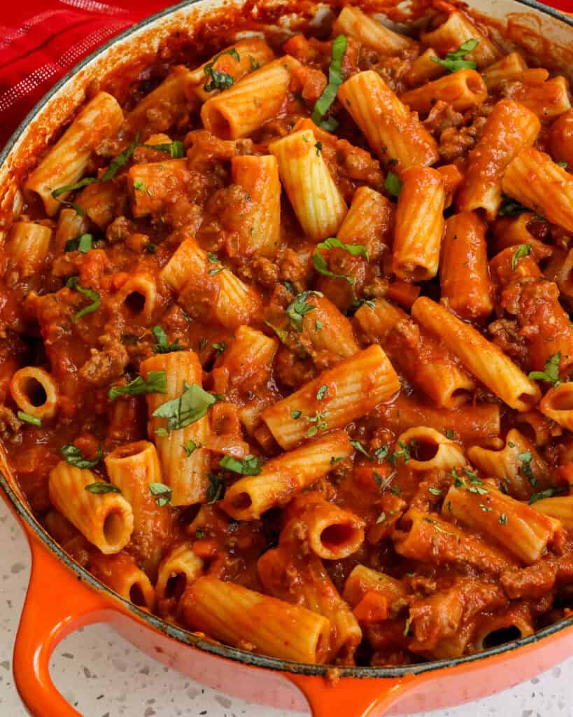Close up of Pasta Bolognese in the pot topped with basil.